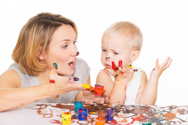 Feliz madre joven y niño con manos pintadas aisladas en blanco.