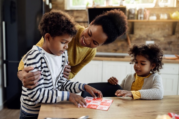 Feliz madre negra y sus hijos poniendo la mesa en el comedor