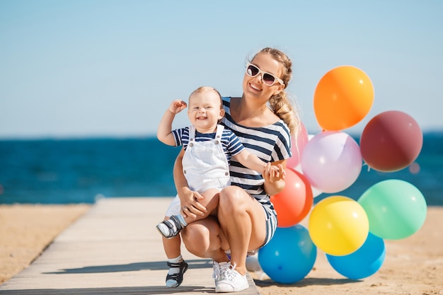 feliz madre con un niño divirtiéndose en la playa cerca del mar