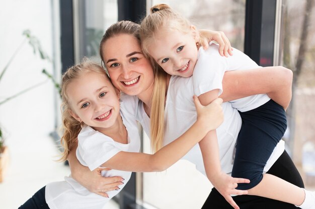 Feliz madre posando con hijas en casa