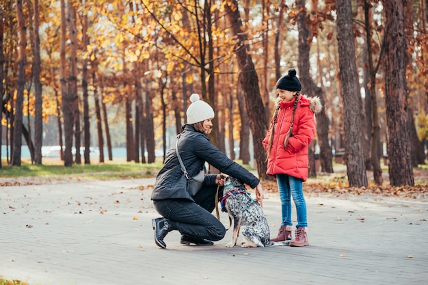 Foto gratuita feliz madre y su hija jugando con perro en el parque otoño