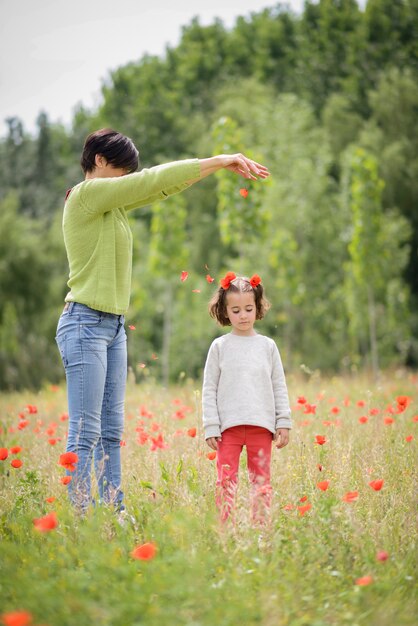 Feliz madre con su pequeña hija en el campo de amapola