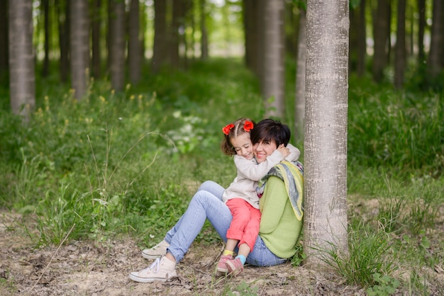 Feliz madre con su pequeña hija en el campo de amapola