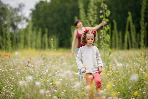 Feliz madre con su pequeña hija en el campo de amapola