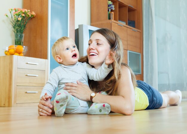 feliz mamá con niño en piso de madera