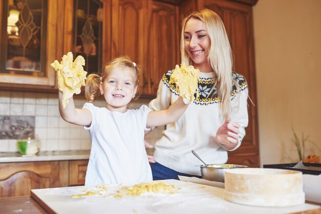 Feliz mamá sonriente en la cocina hornea galletas con su hija.