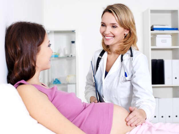 Feliz médico cuidando a la joven embarazada en el hospital