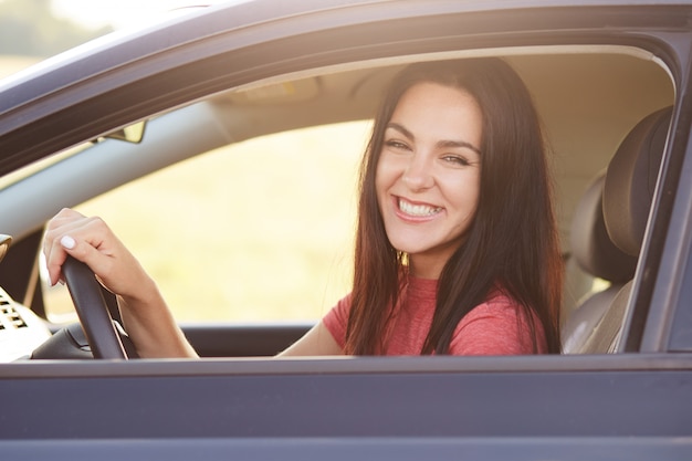 Feliz morena mujer conductora con amplia sonrisa