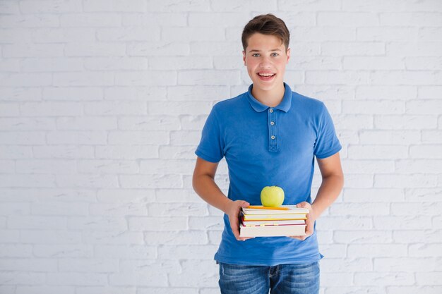 Feliz muchacho adolescente con libros