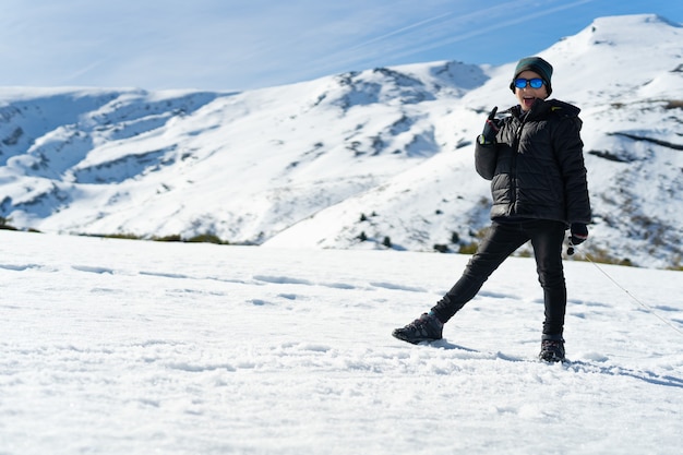 Foto gratuita feliz muchacho caucásico con ropa de abrigo en la montaña nevada en el invierno