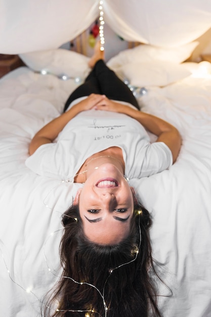 Feliz mujer acostada en la cama con luces de ferry en el pelo