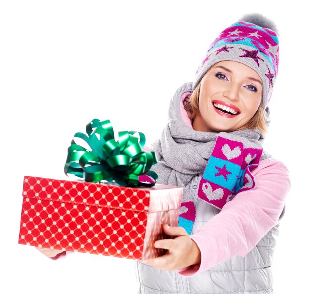 Feliz mujer adulta dando un regalo de Navidad en una ropa de abrigo de invierno aislado en blanco