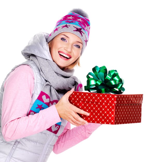 Feliz mujer adulta dando un regalo de Navidad en una ropa de abrigo de invierno aislado en blanco