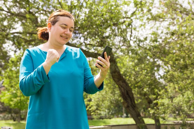 Feliz mujer afortunada con mensaje de lectura de teléfono móvil