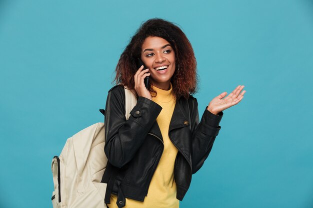 Feliz mujer africana en chaqueta de cuero con mochila