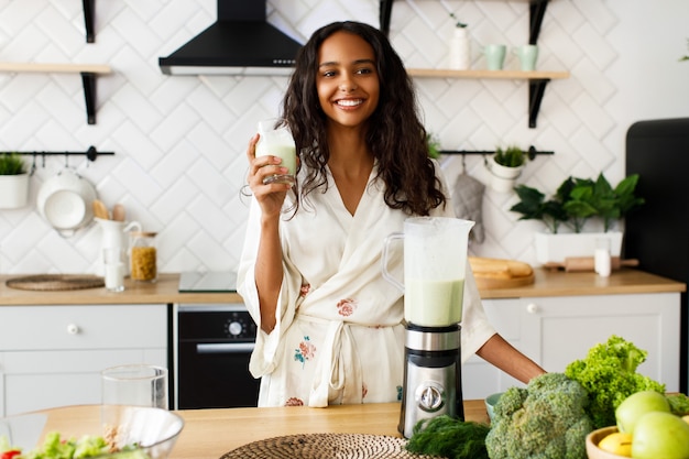 Feliz mujer africana está bebiendo batido en la mañana