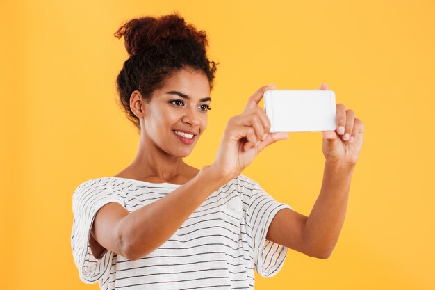 Feliz mujer africana haciendo fotos en el teléfono