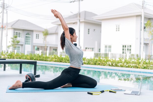 Feliz mujer asiática haciendo ejercicio de estiramiento y entrenamiento de yoga por la mañana en casa