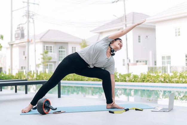 Feliz mujer asiática haciendo ejercicio de estiramiento y entrenamiento de yoga por la mañana en casa