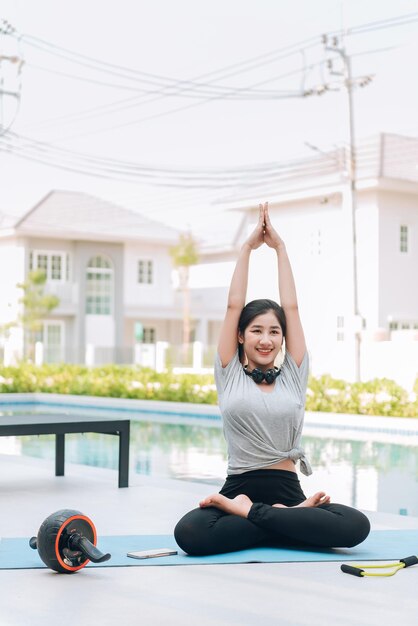 Feliz mujer asiática haciendo ejercicio de estiramiento y entrenamiento de yoga por la mañana en casa