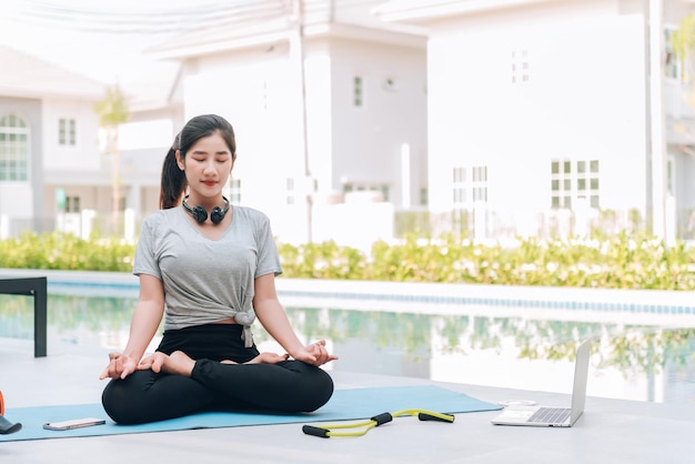 Foto gratuita feliz mujer asiática haciendo ejercicio de estiramiento y entrenamiento de yoga por la mañana en casa