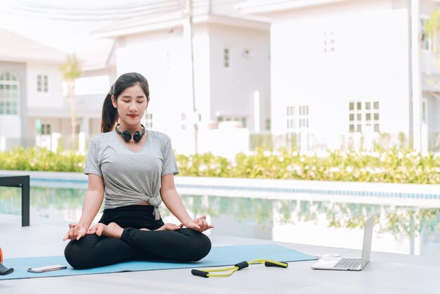 Feliz mujer asiática haciendo ejercicio de estiramiento y entrenamiento de yoga por la mañana en casa