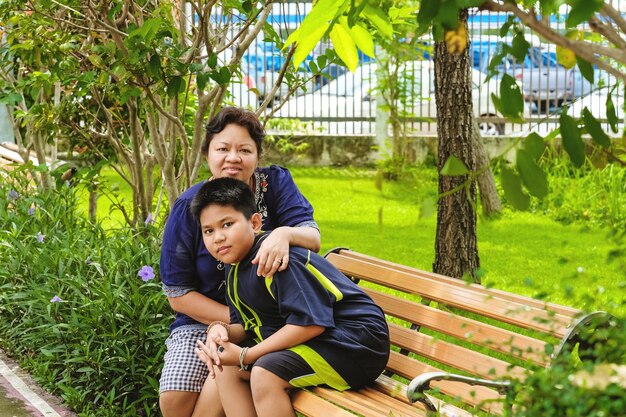 Feliz mujer asiática madre sentada con su hijo y sentada en el parque