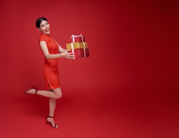 Foto gratuita feliz mujer asiática sonriente vestida con traje tradicional rojo dando caja de regalo para bendecir el año nuevo chino