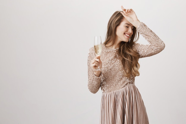 Feliz mujer bailando en vestido de noche con copa de champán