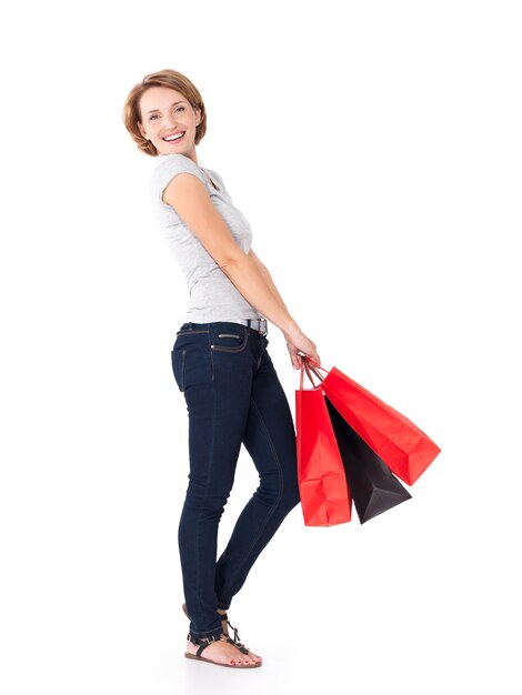 Feliz mujer blanca con bolsas de la compra en blanco - retrato completo