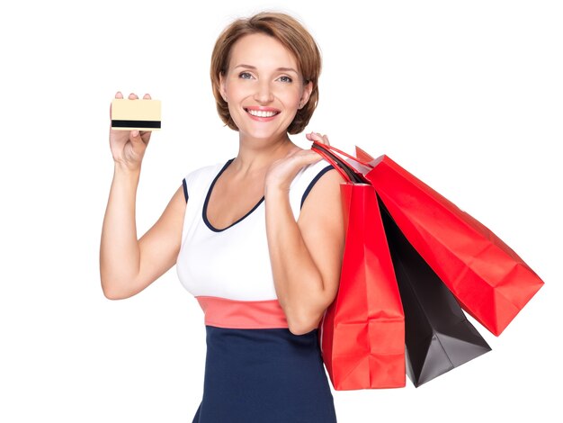 Feliz mujer blanca con bolsas de la compra y tarjeta de crédito sobre un espacio en blanco