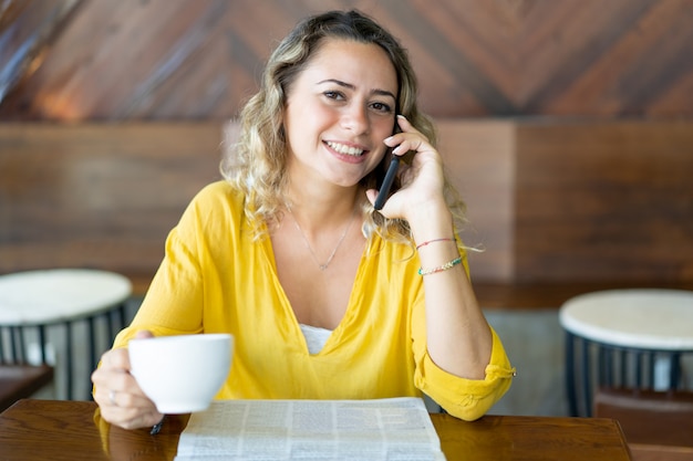 Feliz mujer bonita en café hablando por teléfono