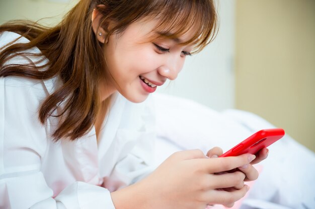 Feliz mujer bonita con smartphone en la cama