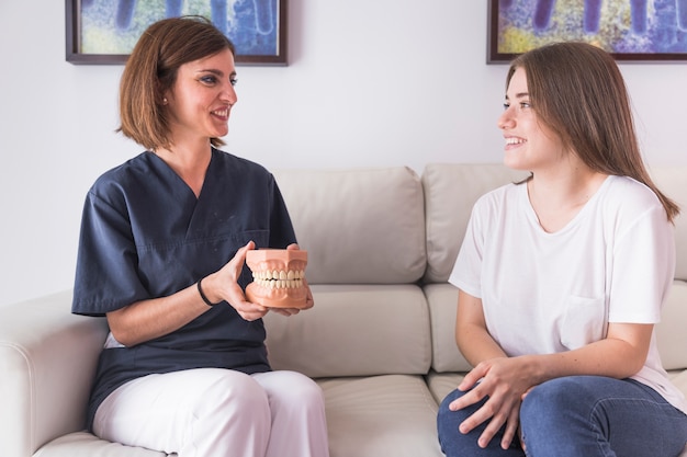 Feliz mujer dentista mostrando los dientes modelo a mujer