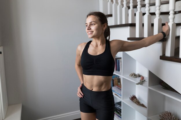 Feliz mujer deportiva posando junto a las escaleras