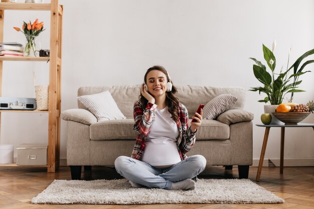 Feliz mujer embarazada meditando y escuchando música relajante en auriculares