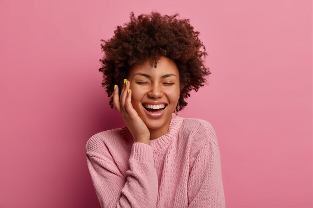 Feliz mujer entusiasta extremadamente positiva toca la mejilla y se ríe sinceramente