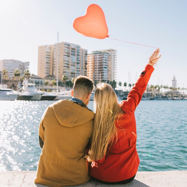 Feliz mujer y hombre de refrigeración en el paseo marítimo