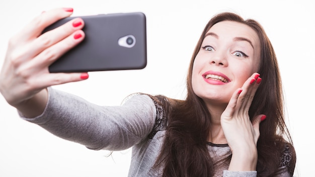 Feliz mujer joven y bonita haciendo selfie en smartphone