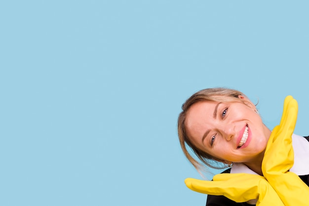 Feliz mujer joven con guante amarillo posando sobre fondo azul