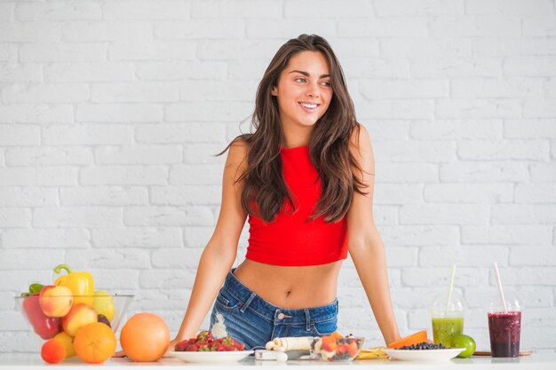 Feliz mujer joven de pie detrás de la mesa con comida sana