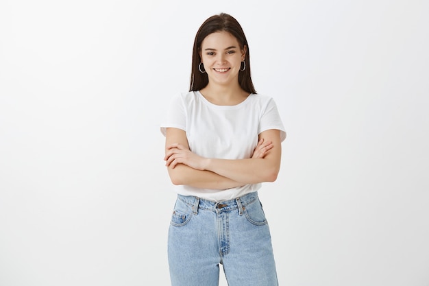 feliz, mujer joven, posar, contra, pared blanca