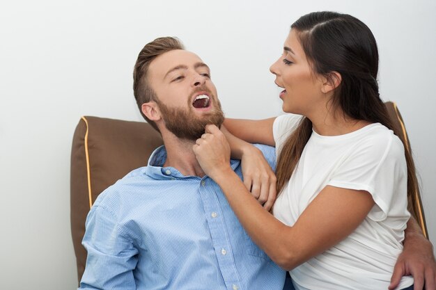 Feliz mujer joven que pellizca la barba de su novio