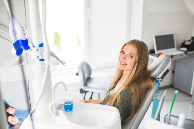 Feliz mujer joven sentada en la silla dental