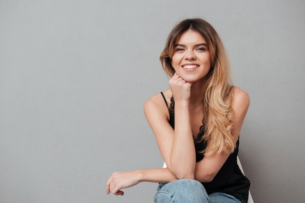 Feliz mujer joven sentada en una silla y posando