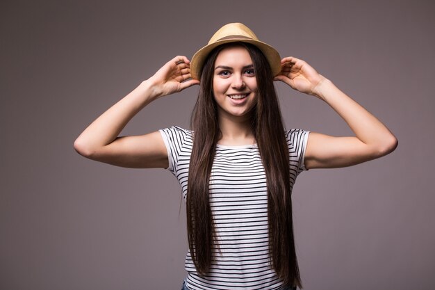 Feliz mujer juguetona vistiendo fedora de paja de verano mirando hacia el lado sobre el hombro