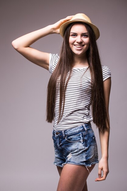 Feliz mujer juguetona vistiendo fedora de paja de verano mirando hacia el lado sobre el hombro