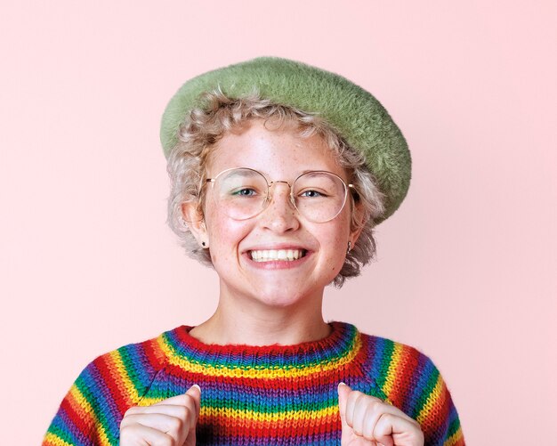 Feliz mujer lesbiana con suéter de arco iris en una maqueta de pared rosa