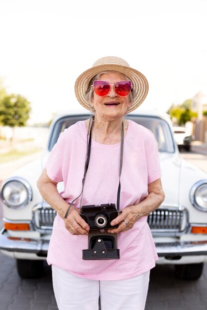 Feliz mujer mayor de pie junto a su coche