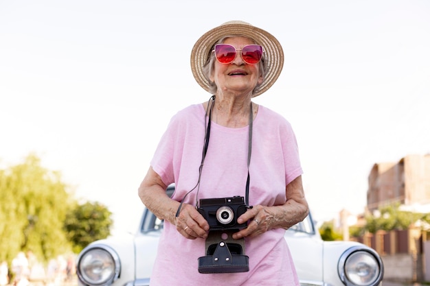 Feliz mujer mayor de pie junto a su coche